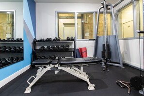 Une salle de sport équipée d’haltères, de bancs et d’appareils d’exercice.