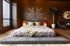 Une chambre à coucher moderne avec un grand lit, un élément décoratif mural, une plante en pot et un miroir.