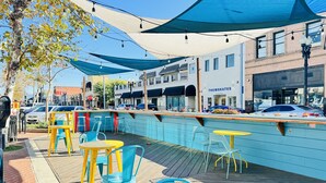 Zona de estar al aire libre con bar junto a la piscina, mesas y sillas.
