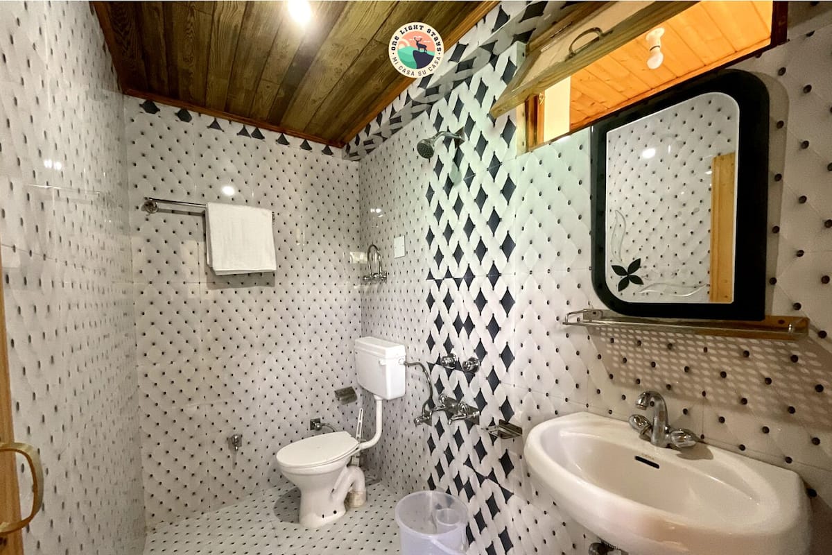 A bathroom with a toilet, sink, and mirror. The walls have a black and white diamond pattern.