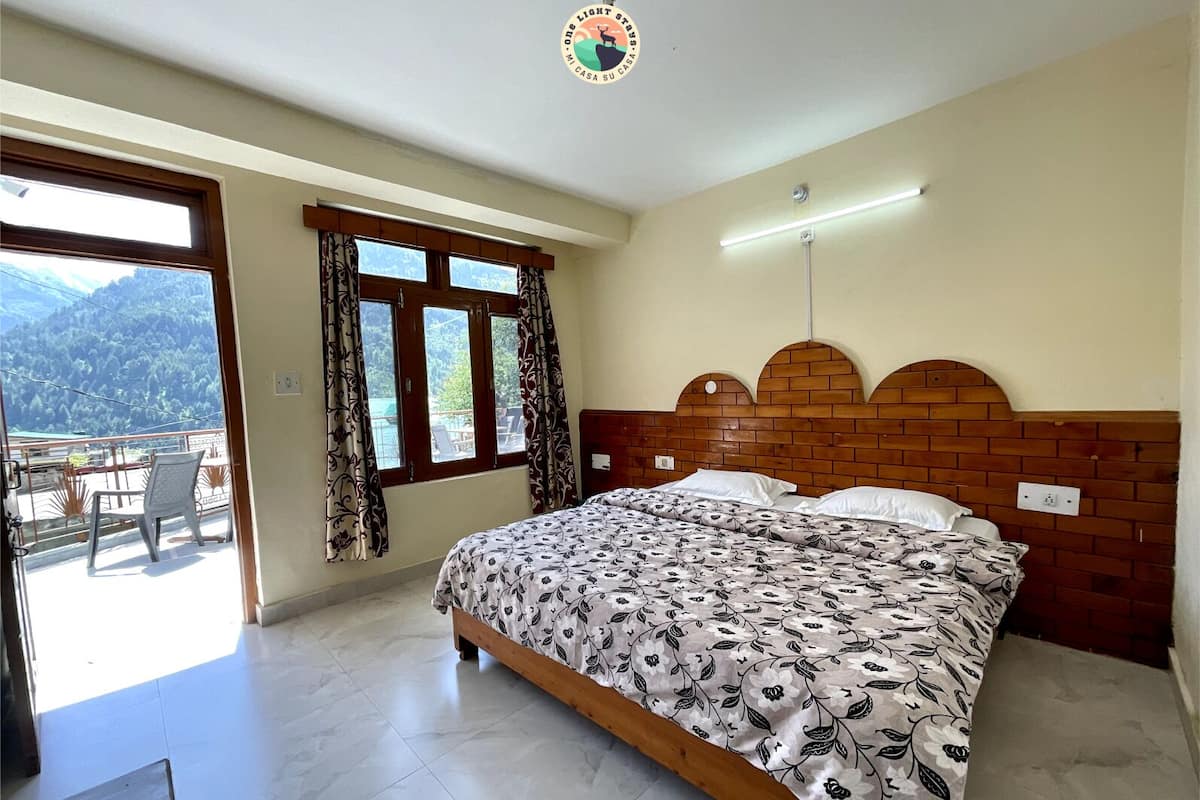 A bedroom with a bed, a window with curtains, a ceiling fan, and a view of mountains.