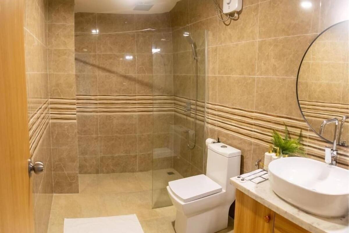 Uma casa de banho moderna com cabine de duche em vidro, sanita e lavatório com toucador.