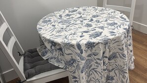A round table with a floral tablecloth, a white chair with a cushioned seat, and a wooden floor. - Home away from home, has all the amenities you need to have a comfortable stay. (Saint Bernard)