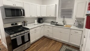 A modern kitchen with white cabinets, stainless steel appliances, and a wooden floor. - Home away from home, has all the amenities you need to have a comfortable stay. (Saint Bernard)