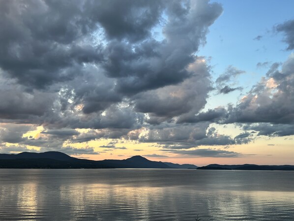 Un lago tranquilo con montañas al fondo y un cielo nublado.
