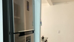 A kitchen with a stainless steel refrigerator, a built-in oven, and a small countertop. - Hermoso Apartamento Mosquera (guayacan)