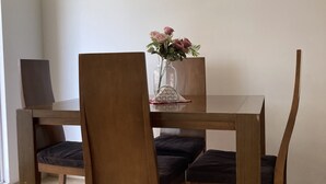 A dining area with a wooden table and chairs, a vase with flowers, and a laptop on the table. - Hermoso Apartamento Mosquera (guayacan)