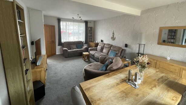 A spacious living room with a large wooden dining table, a sofa set, and a bookshelf. - Beautiful 3-bed House in Romford (Romford)