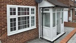 A brick house with a white door and window shutters, a satellite dish, and a paved driveway. - Beautiful 3-bed House in Romford (Romford)
