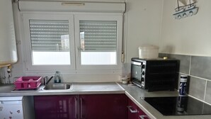 Et lille køkken med et vindue, en mikrobølgeovn og en vask.
