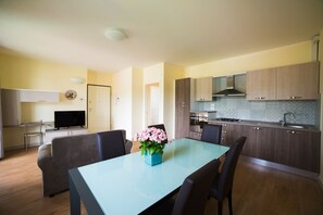 Cozy living area with a comfortable sofa and dining table for two, featuring a vase of flowers and modern kitchen with ample counter space.