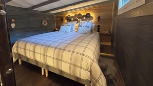 A bedroom with a large bed, wooden walls, and a sloped ceiling.