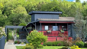 A two-story building with a red and black exterior, surrounded by lush greenery.