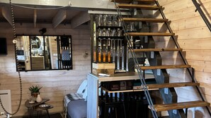 A modern loft with a wooden interior, a staircase, and a bar area with glassware.