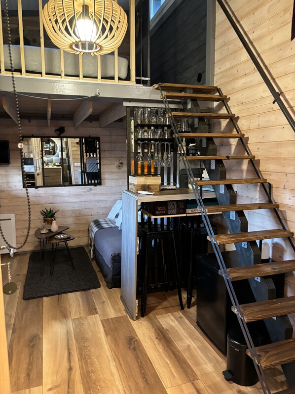 A modern loft with a wooden interior, a staircase, and a bar area with glassware.
