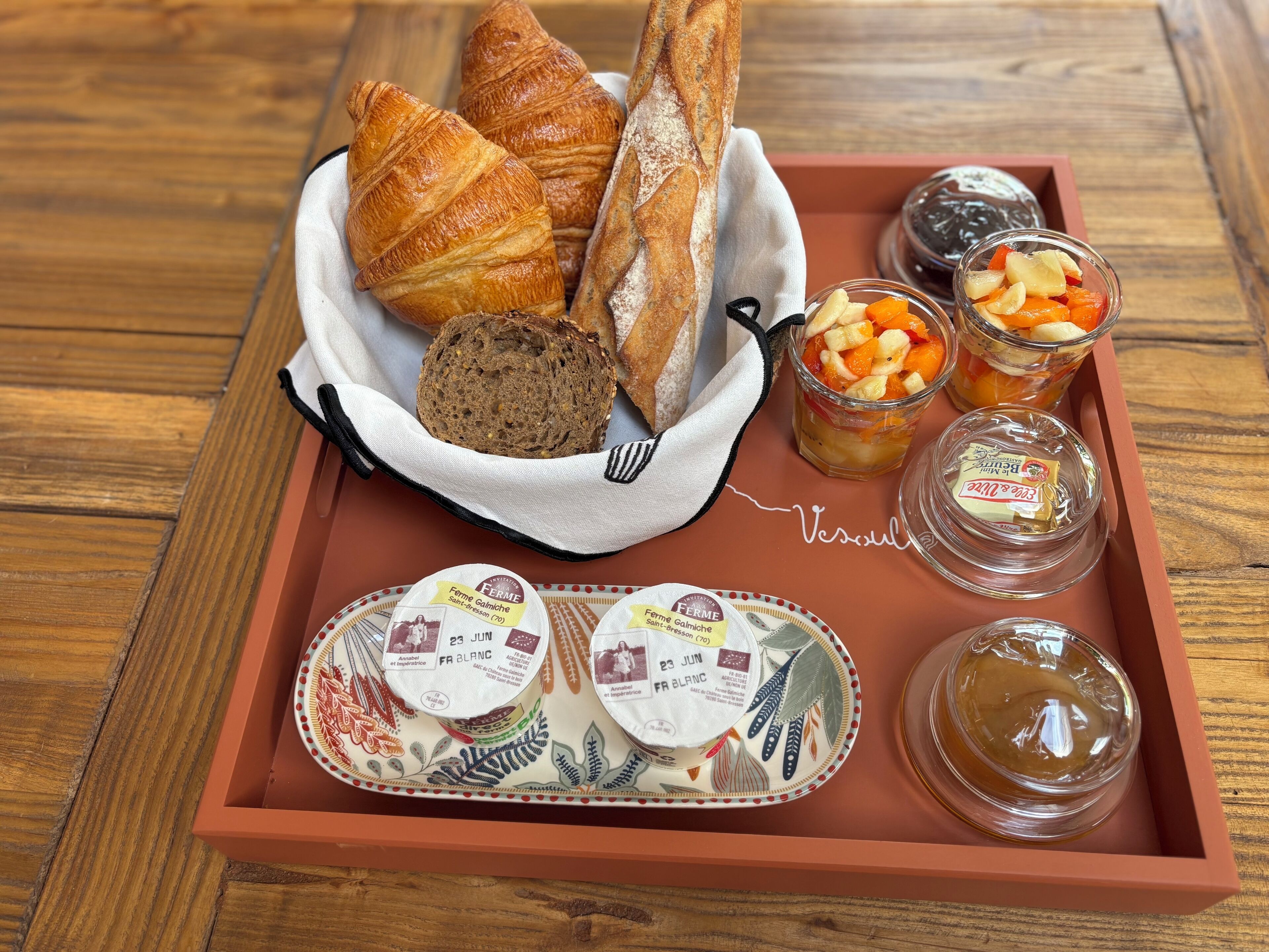 En bakke med croissanter, brød, frugtmarmelade, marmelade, ost og smør.