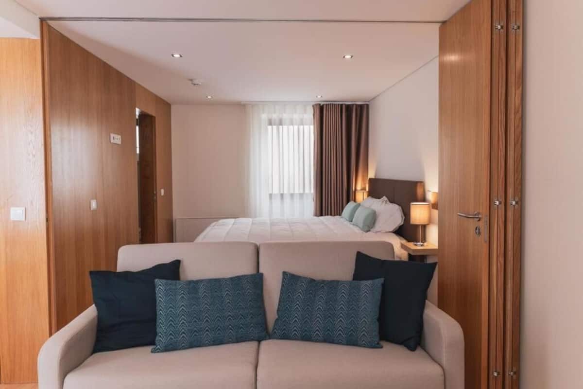 Ein Hotelzimmer mit einem Bett, einer Couch, Holzschränken und einem Nachttisch mit Lampe.