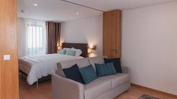 Una habitación de hotel moderna con una cama, un sofá y un armario de madera.