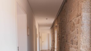 A hallway with a stone wall on one side and a white door on the other.