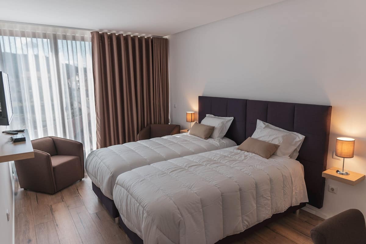 Ein Hotelzimmer mit zwei Betten, einem Schreibtisch, einem Stuhl und einem Fernseher.