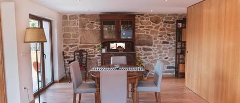 A dining area with a stone wall, wooden cabinets, and a round table with chairs.
