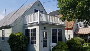 A two-story house with a gabled roof, white exterior, and a small balcony. - Sandcastle park! Basketball, Tennis, beach, mini golf, ice cream & restaurants! (Ocean City)