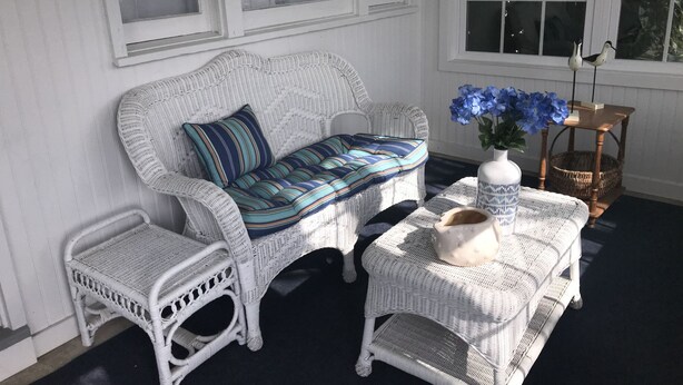 A wicker sofa with striped cushions, a matching armchair, and a small table with a vase of flowers. - Sandcastle park! Basketball, Tennis, beach, mini golf, ice cream & restaurants! (Ocean City)