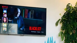 Un salon moderne avec un téléviseur diffusant une émission intitulée « BLACKLIST ».