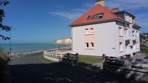 A coastal building with a red roof, a balcony, and a view of the sea.