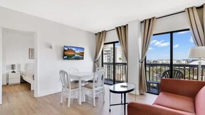 A modern apartment with a dining area, a sofa, and a balcony with a city view. - INTERNATIONAL dr/UNIVERSAL 2 BEDROOMS KING SUITE with free parking  (Orlando)