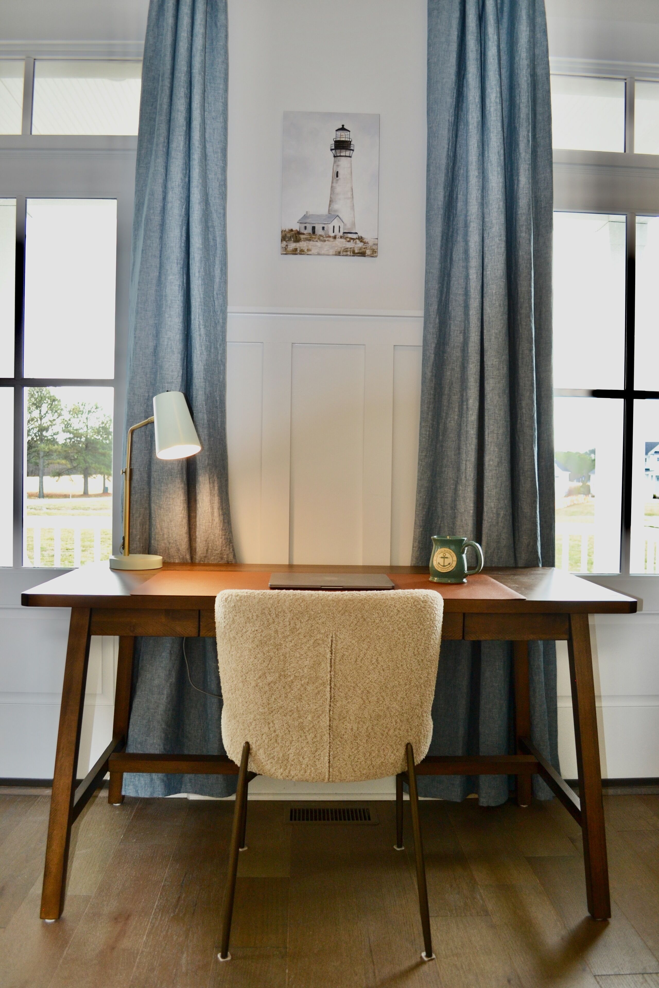 A room with a wooden desk, a chair, a lamp, and a mug.