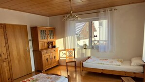 Une pièce chaleureuse avec deux lits en bois, une armoire en bois, une chaise et une fenêtre avec des rideaux.