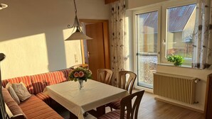 Un coin repas accueillant avec une table et des chaises en bois, un canapé et une fenêtre agrémentée de rideaux.