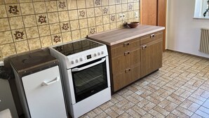 Une cuisine équipée d’une cuisinière, d’un four et de meubles de rangement en bois.