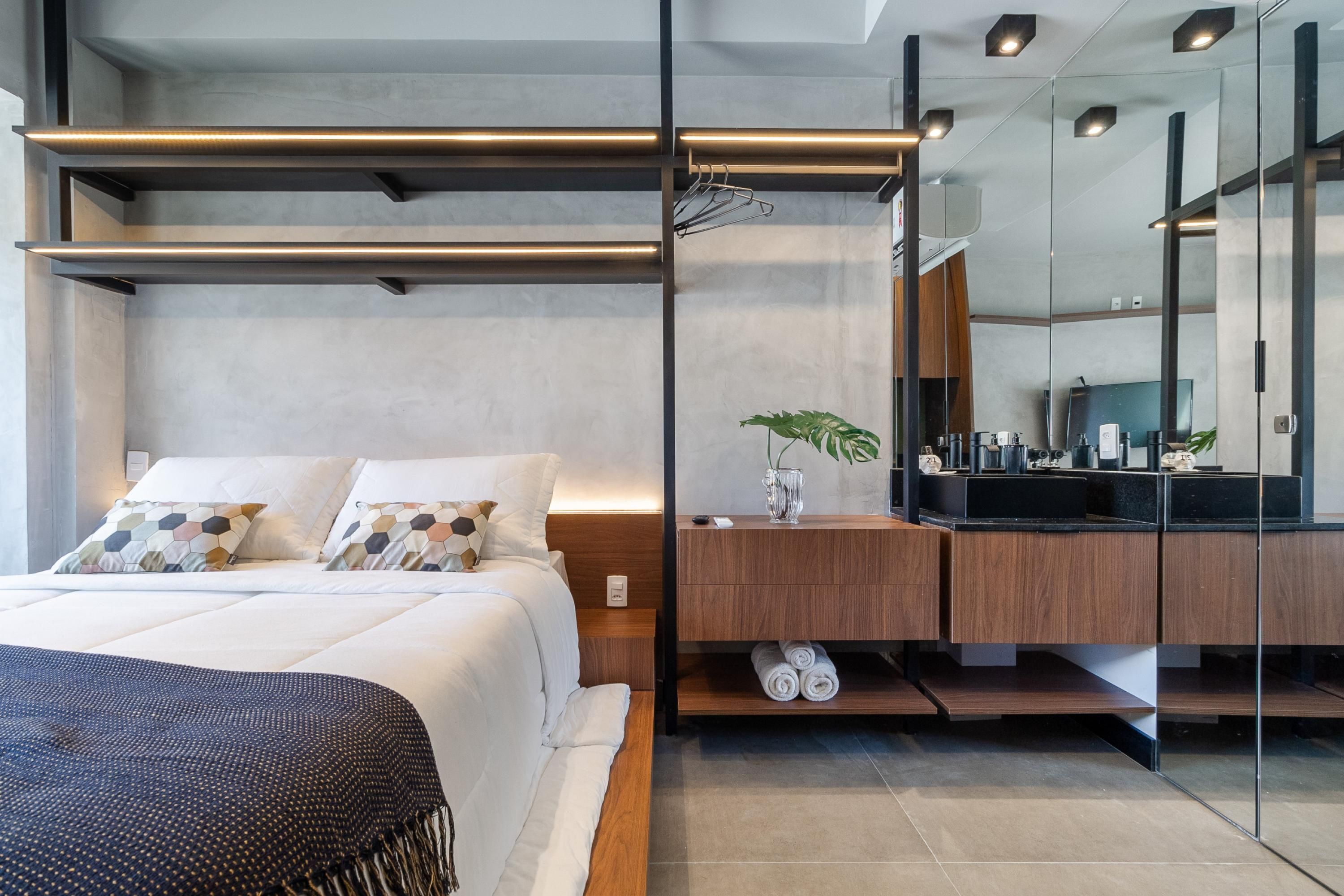 Ein modernes Schlafzimmer mit einem großen Bett, einem Nachttisch aus Holz, einem Spiegel und einem eingebauten Kleiderschrank.