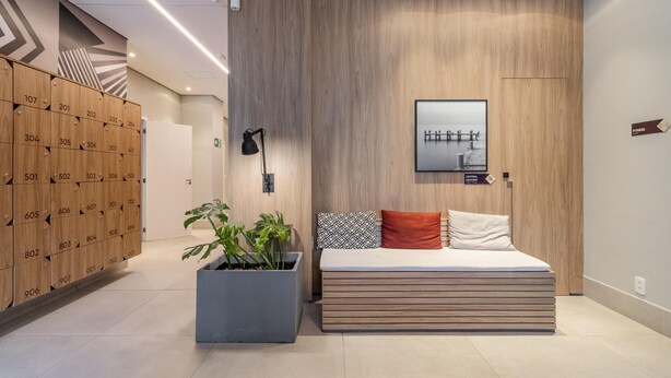 A modern hotel room with a wooden wall, a bed with patterned pillows, a potted plant, and a view of a bridge. - Seng 106 in S o Paulo (São Paulo)