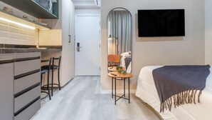 A modern kitchen with a microwave, a small dining area with a table and chairs, and a bed with a blanket. - Seng 106 in S o Paulo (São Paulo)