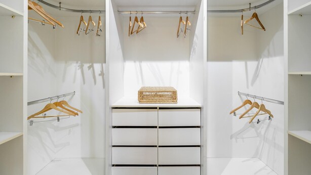 A walk-in closet with multiple wooden hangers and a wicker basket on a central shelf. - Ai78-2506 in S o Paulo (São Paulo)