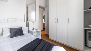 A modern bedroom with a bed, a wardrobe, and a small kitchenette. - Ai78-2506 in S o Paulo (São Paulo)
