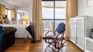 A modern living room with a wooden floor, a brown leather sofa, a blue chair, a white cabinet, and a balcony with curtains. - Ai78-2506 in S o Paulo (São Paulo)