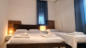 A hotel room with two beds, each with a wooden headboard, white linens, and a lamp on the nightstand. - Villa by the sea, perfect for families (Mascali)