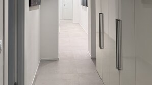 A modern hallway with white walls, a tiled floor, and recessed ceiling lights. There are doors on the left and a long corridor leading to a room in the distance. - Villa by the sea, perfect for families (Mascali)