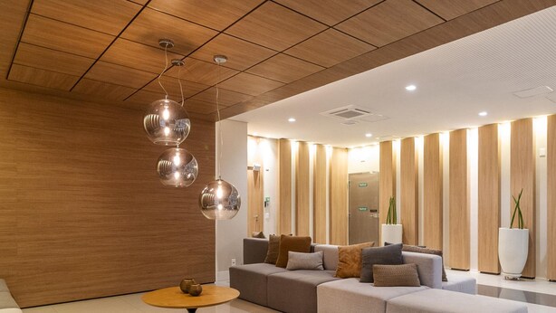 A modern lobby with a wooden ceiling, a sectional sofa, a round coffee table, and a large potted plant. - Landingcb 1301 in S o Paulo (São Paulo)