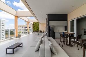 Relax in this open-plan living space with a balcony offering city views, a sofa, and a compact kitchen.