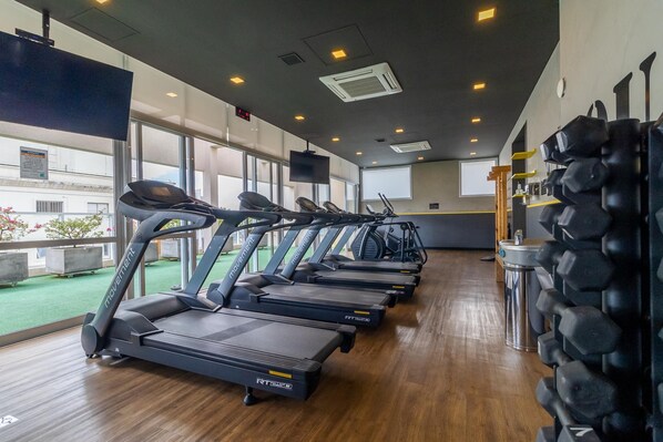 A gym with treadmills, weights, and a large window.