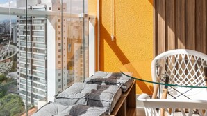 A balcony with a view of a cityscape, a white chair, and a table with towels. - Landingcb 1301 in S o Paulo (São Paulo)