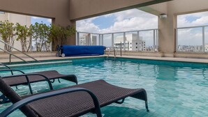 A rooftop pool with clear blue water, surrounded by lounge chairs and a view of the city skyline. - Landingcb 1301 in S o Paulo (São Paulo)