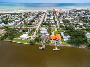 An aerial view of a coastal residential area with houses, a marina, and a beach.