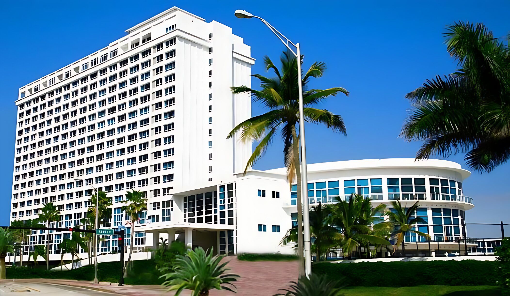 A modern hotel with a large white building and a curved structure with blue-tinted windows.