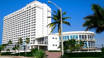 A modern hotel with a large white building and a curved structure with blue-tinted windows.